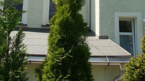 Un immeuble à plusieurs étages, doté d’une façade de couleur claire, de nombreuses fenêtres à encadrements blancs et d’un système de gouttières apparent.