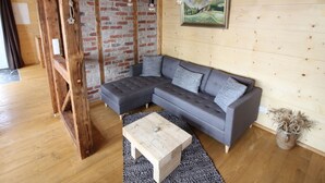A cozy living room with a gray sectional sofa, a wooden coffee table, and a rustic brick wall. - Anno Dazumal by Interhome (Klingenthal)