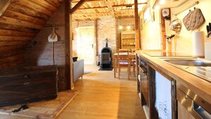 A rustic kitchen with wooden beams, a brick wall, a fireplace, and modern appliances. - Anno Dazumal by Interhome (Klingenthal)