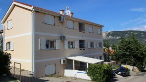Un edificio de varios pisos con techo plano, varias ventanas con contraventanas y un pequeño balcón.