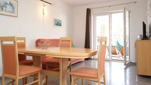 Un área de comedor con una mesa y sillas, un sofá y un televisor sobre un mueble.