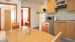 Cocina compacta con armarios de madera, microondas, cafetera y refrigerador.