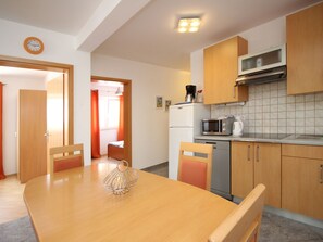 A compact kitchen with wooden cabinets, a microwave, a coffee maker, and a refrigerator. - Appartement in Baška mit Eigener Terrasse by Interhome (Krk/Baška)