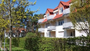 Un edifici residencial de diverses plantes amb balcons, envoltat de vegetació i arbres.