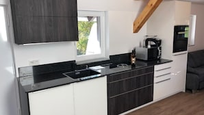 Una cocina moderna con armarios oscuros, encimera negra y ventana que proporciona luz natural.