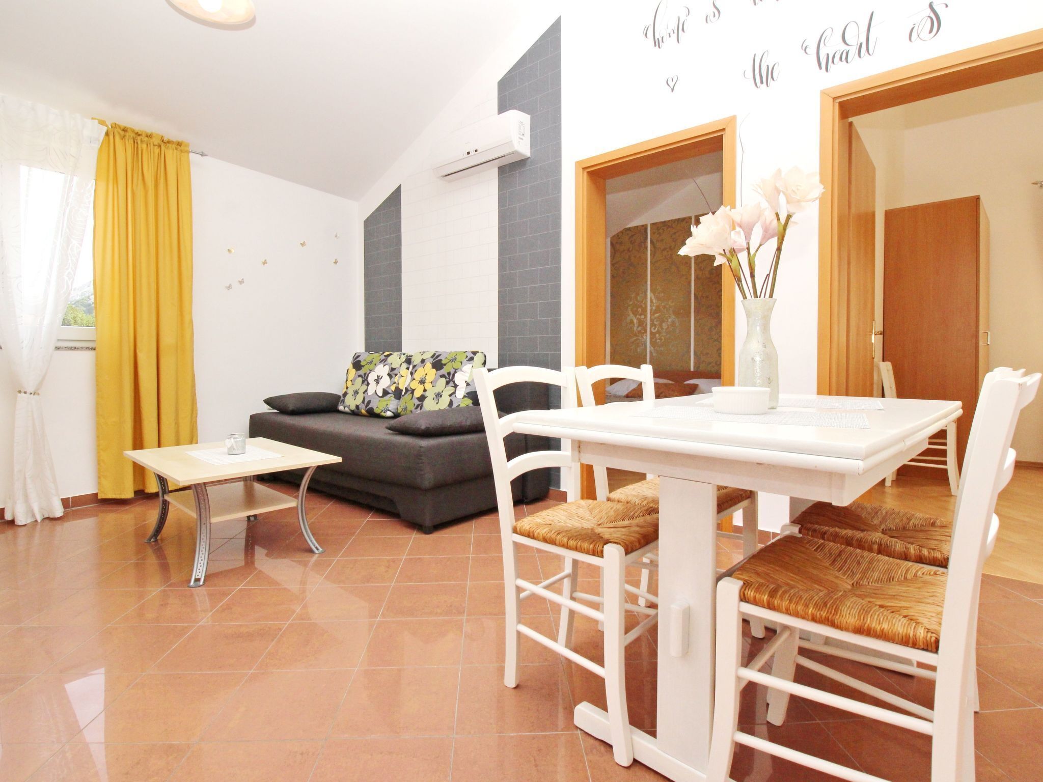 A modern living room with a sofa, a dining table with chairs, and a decorative vase.