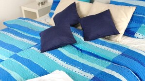 Ein Bett mit einer blau-weiß gestreiften Tagesdecke, zwei Kissen und ein weißes Handtuch.