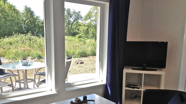 Ein Wohnzimmer mit Fernseher, Tisch und zwei Stühlen.
