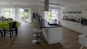 Een moderne keuken met witte kasten, een centraal eiland en een eethoek met een groene tafel en stoelen.