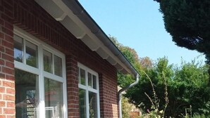 Een huis met een bakstenen gevel, grote glasramen en een houten terras.