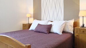 A neatly made bed with a purple blanket and pillows, two bedside tables with lamps, and a wall with a wavy pattern. - Apartment Brnic8 by Interhome (Krk/Baška)