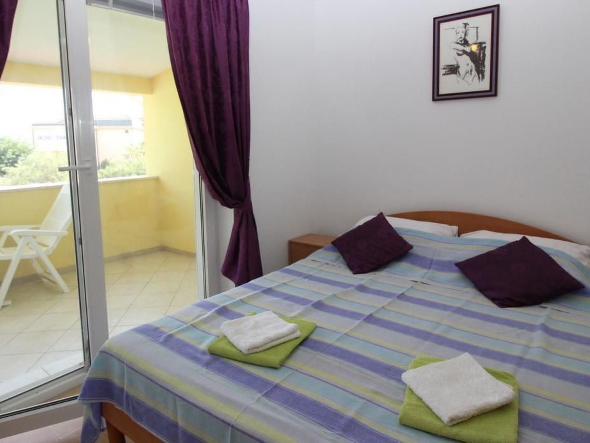 A hotel room with a bed, pillows, and a window with purple curtains.