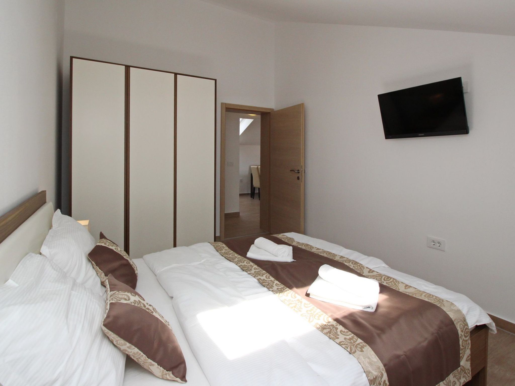 Une chambre d’hôtel comprenant un lit, une armoire, un téléviseur et une porte donnant sur une autre pièce.