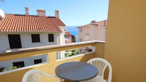 A balcony with a round table and two white chairs, overlooking a cityscape with terracotta roofs. - Appartement in Baška mit Eigenem Balkon by Interhome (Krk/Baška)