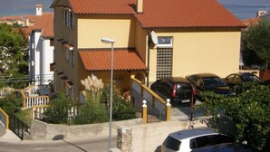 A yellow building with a red roof, a staircase, and a parking area with cars. - Appartement in Baška mit Eigenem Balkon by Interhome (Krk/Baška)