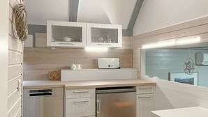 Una cucina compatta con elettrodomestici integrati, un piano di lavoro in legno e un angolo ristoro con tavolo.