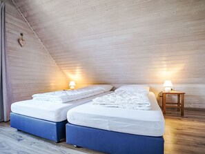 Een kamer met twee bedden, een houten plafond en twee bedlampjes.