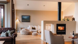 Ein modernes Wohnzimmer mit Kamin, Sofas und Holzboden.