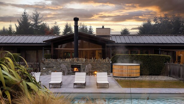 Ein moderner Außenbereich mit Pool, Liegestühlen, Kamin und Whirlpool.