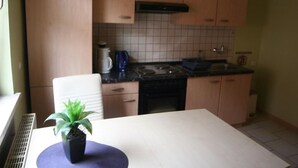 A kitchen with wooden cabinets, a stove, and a coffee maker. - Gästehaus Tröbs by Interhome (Ilfeld)