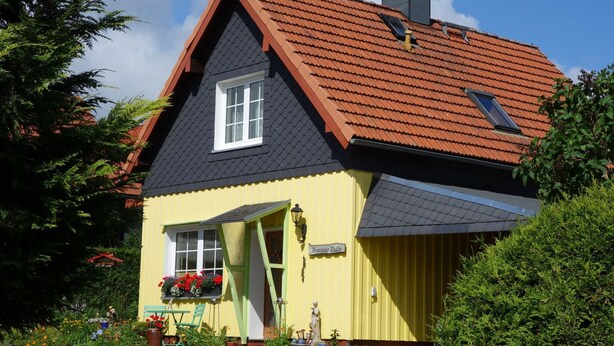 Um edifício amarelo com telhado preto e uma pequena janela.