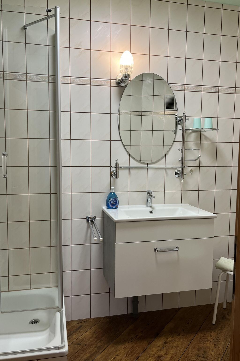 A bathroom with a white sink, mirror, and shower.