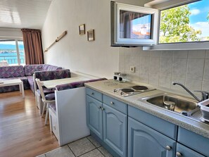 A compact kitchen with a built-in stove, a sink, and a window overlooking a scenic view. - direkt am Strand by Interhome (Krk/Milohnići)