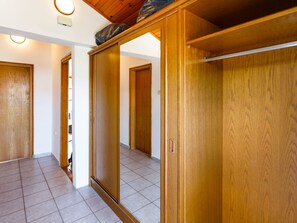 A room with wooden wardrobes, a tiled floor, and a ceiling with wooden beams. - direkt am Strand by Interhome (Krk/Milohnići)