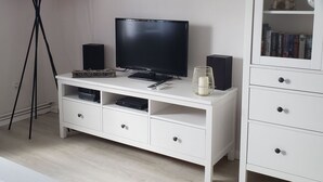 Uma unidade de entretenimento branca com uma TV de tela plana, caixas de som e um controle remoto.