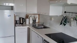 Uma cozinha moderna com armários brancos, lava-louças embutida, fogão e pia.