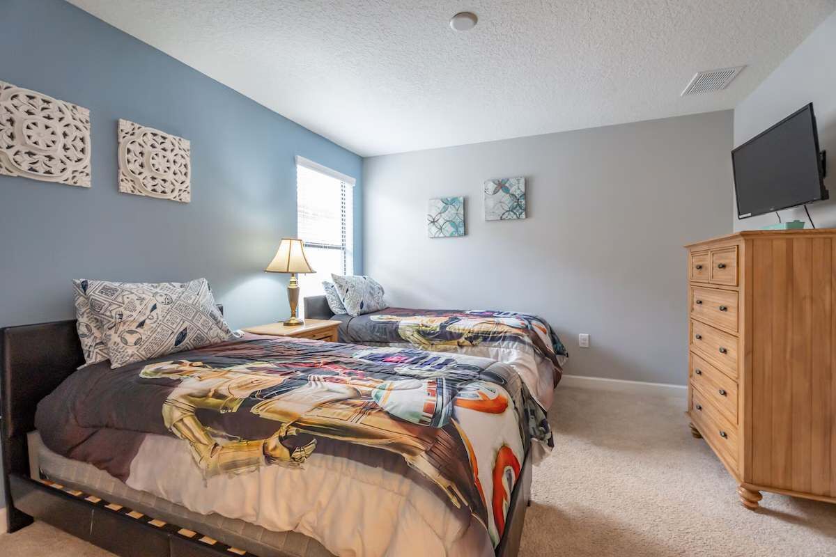 A bedroom with two beds, a dresser, a TV, and decorative wall art.
