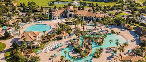 A resort with a large pool area, multiple lounge chairs, and a golf course in the background.