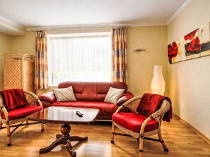 A living room with a red sofa, two wicker armchairs, a coffee table, and a painting on the wall. - Fewo 4 Schneider · Südstadt · Parkplatz · WLAN by Interhome (Görlitz)