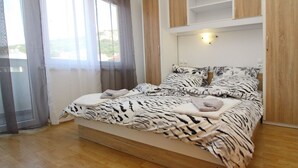 A bedroom with a bed, curtains, a window, and wooden paneling. - Appartement in Baška mit Eigenem Balkon by Interhome (Krk/Baška)