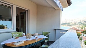 A balcony with a table set for two, chairs, and a view of the sea and hills. - Appartement in Baška mit Eigenem Balkon by Interhome (Krk/Baška)