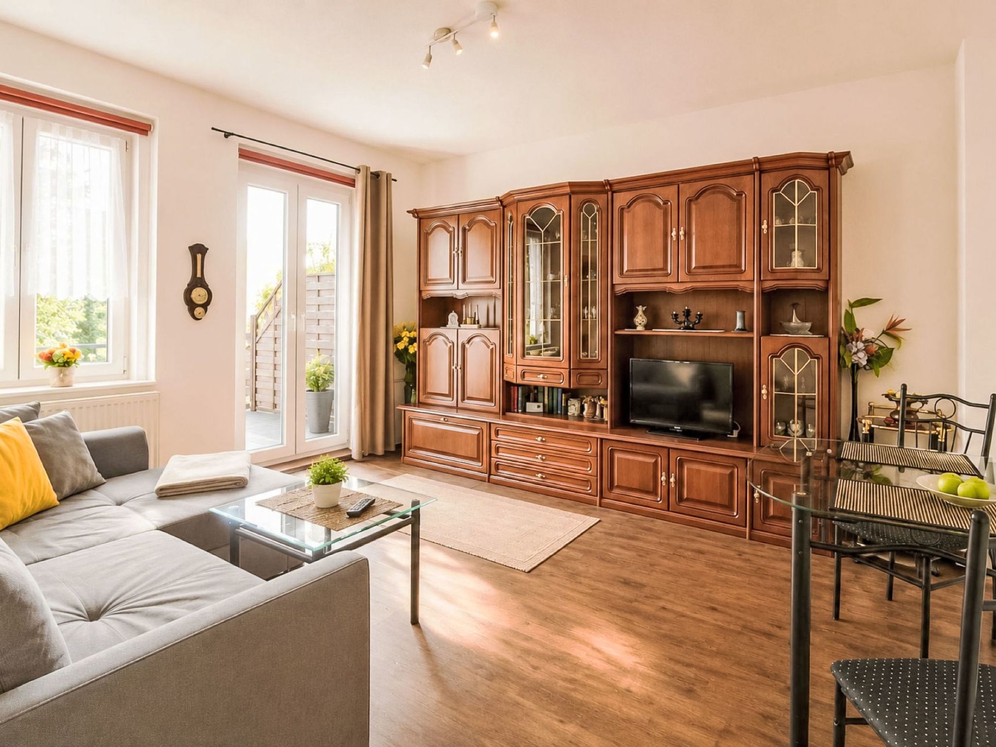 Uma sala de estar moderna com sofá, mesa de centro, televisão e armários de madeira.