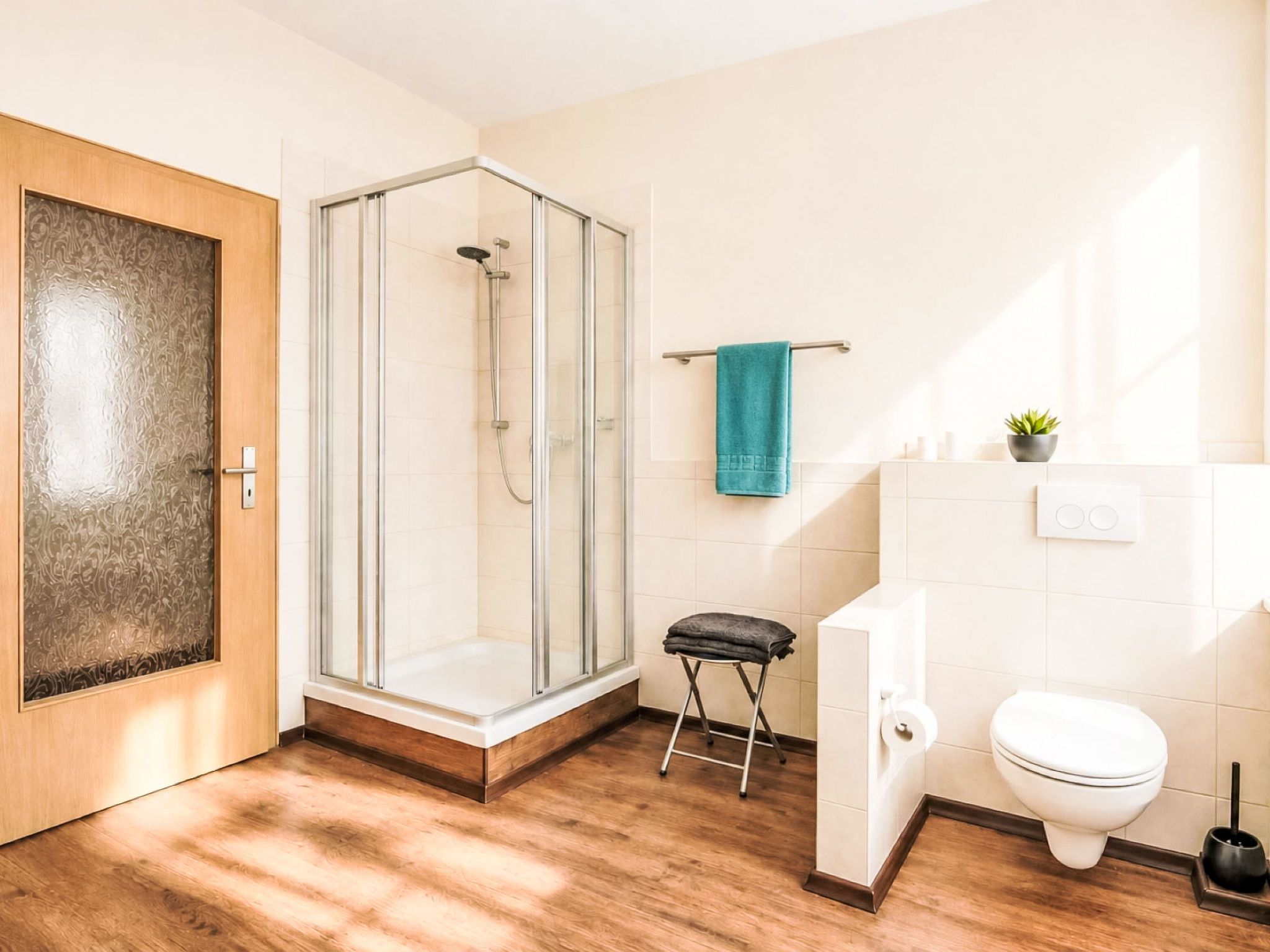 Une salle de bain moderne avec une douche à parois de verre, des toilettes et un petit tabouret.