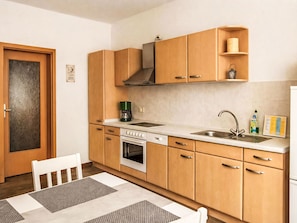 Une cuisine compacte avec des meubles en bois, un four encastré, une machine à café et un évier.