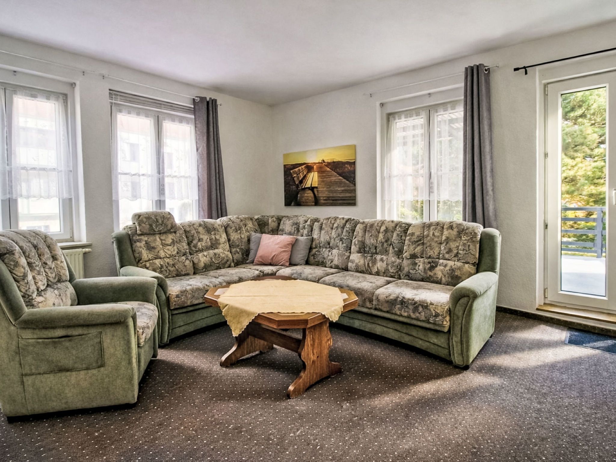 Ein Wohnzimmer mit einem Ecksofa, einem kleinen runden Tisch und einem Bild an der Wand.