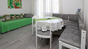 A room with a dining table, a sofa, and a green bedspread. - Fantov Zarok A4 br.3 by Interhome (Krk/Baška)