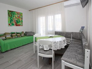A room with a dining table, a sofa, and a green bedspread. - Fantov Zarok A4 br.3 by Interhome (Krk/Baška)