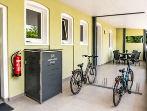 A covered outdoor area with a bicycle charging station, a fire extinguisher, and a seating area with tables and chairs. - Fewo 2 Schneider – Südstadt · Dachterrasse WLAN by Interhome (Görlitz)