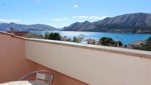 A balcony with a table and chairs, overlooking a lake and mountains. - in Baška mit Eigenem Balkon by Interhome (Krk/Baška)
