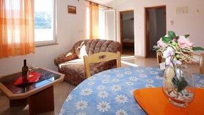 A room with a floral-patterned table, a sofa, and a vase with flowers. - in Baška mit Eigenem Balkon by Interhome (Krk/Baška)