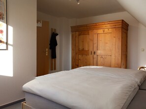 A bedroom with a bed, wooden wardrobe, and a door with a coat hanging. - in idylischer Lage by Interhome (Groß Schoritz)