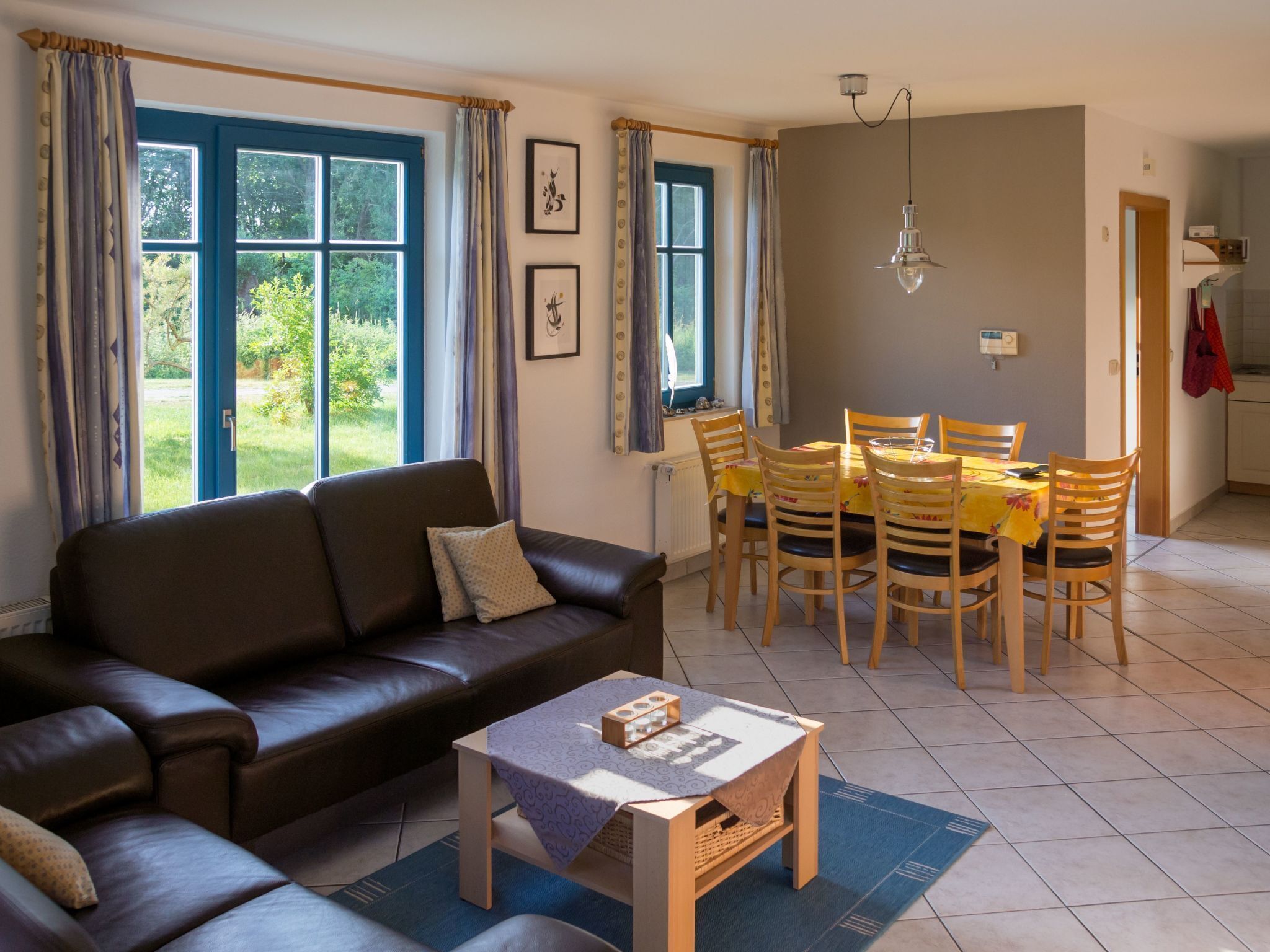A living room with a sofa, a coffee table, and a dining area with chairs and a table.