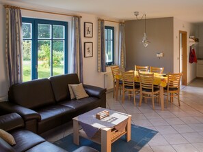 A living room with a sofa, a coffee table, and a dining area with chairs and a table. - in idylischer Lage by Interhome (Groß Schoritz)