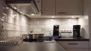 Una cocina moderna con estufa, cafeteras y un salpicadero de azulejos.