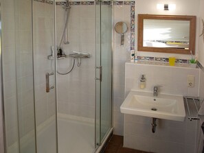 A bathroom with a glass-enclosed shower, a sink with a mirror above it, and a tiled backsplash. - in idylischer Lage by Interhome (Groß Schoritz)