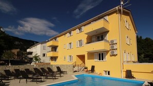A yellow building with a swimming pool and lounge chairs. - Gorica II A2+2 br.2 by Interhome (Krk/Baška)